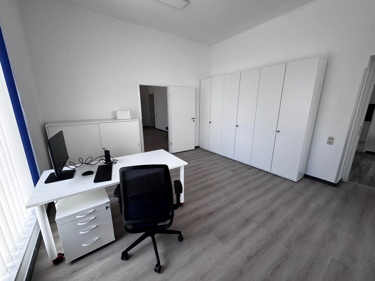 Arbeitsplatz im Studienzentrum Naunhof mit Schreibtisch, Bildschirm und Aktenschränken