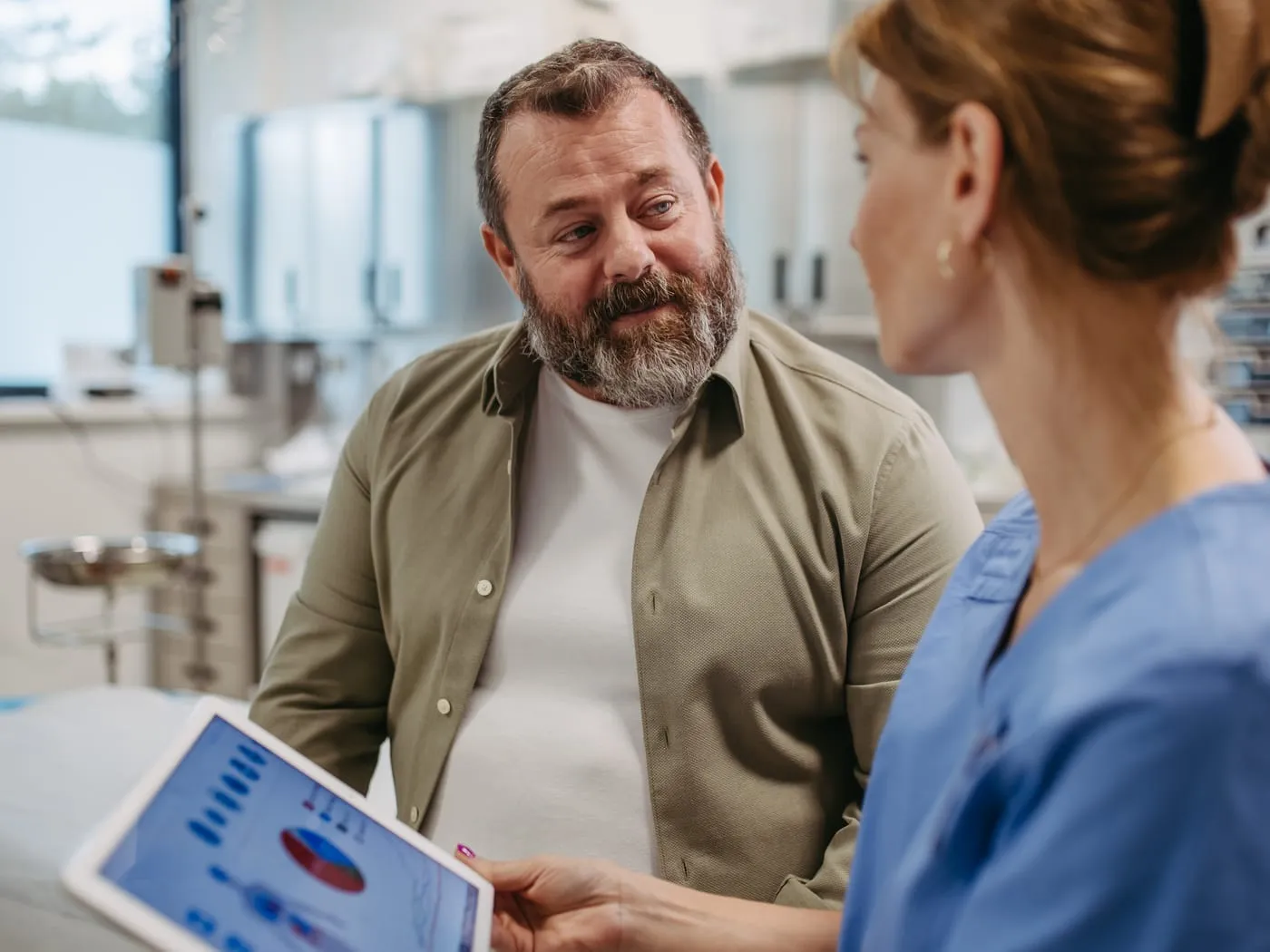 Pflegekraft bespricht mit einem Patienten Werte auf einem Tablet